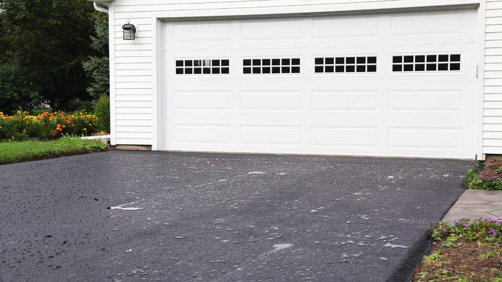 Freshly sealcoated asphalt driveway in front of a home garage completed by Blacktop Services in Massachusetts
