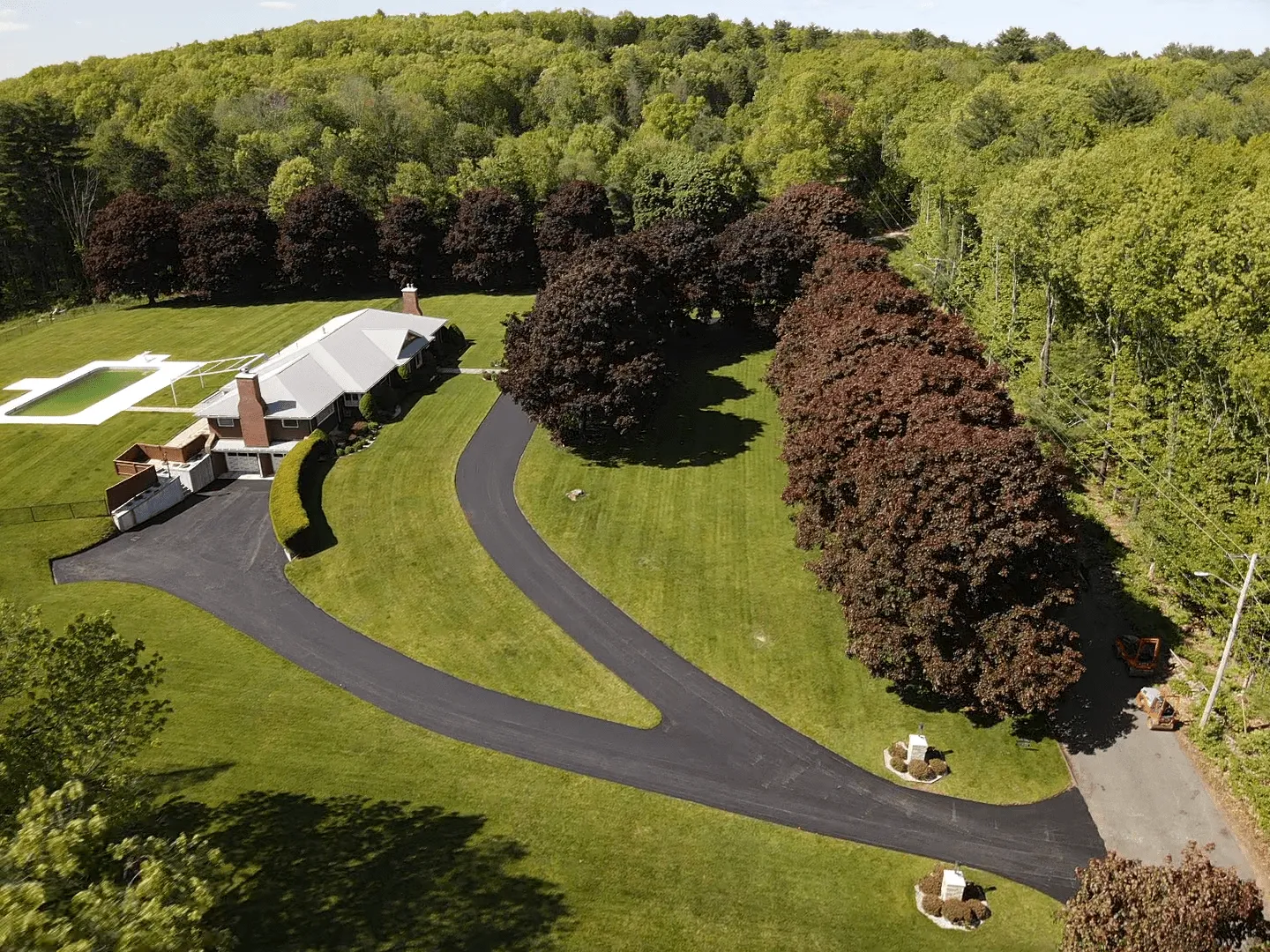 Aerial view of a large residential property with a newly paved asphalt long driveway installation in Massachusetts.