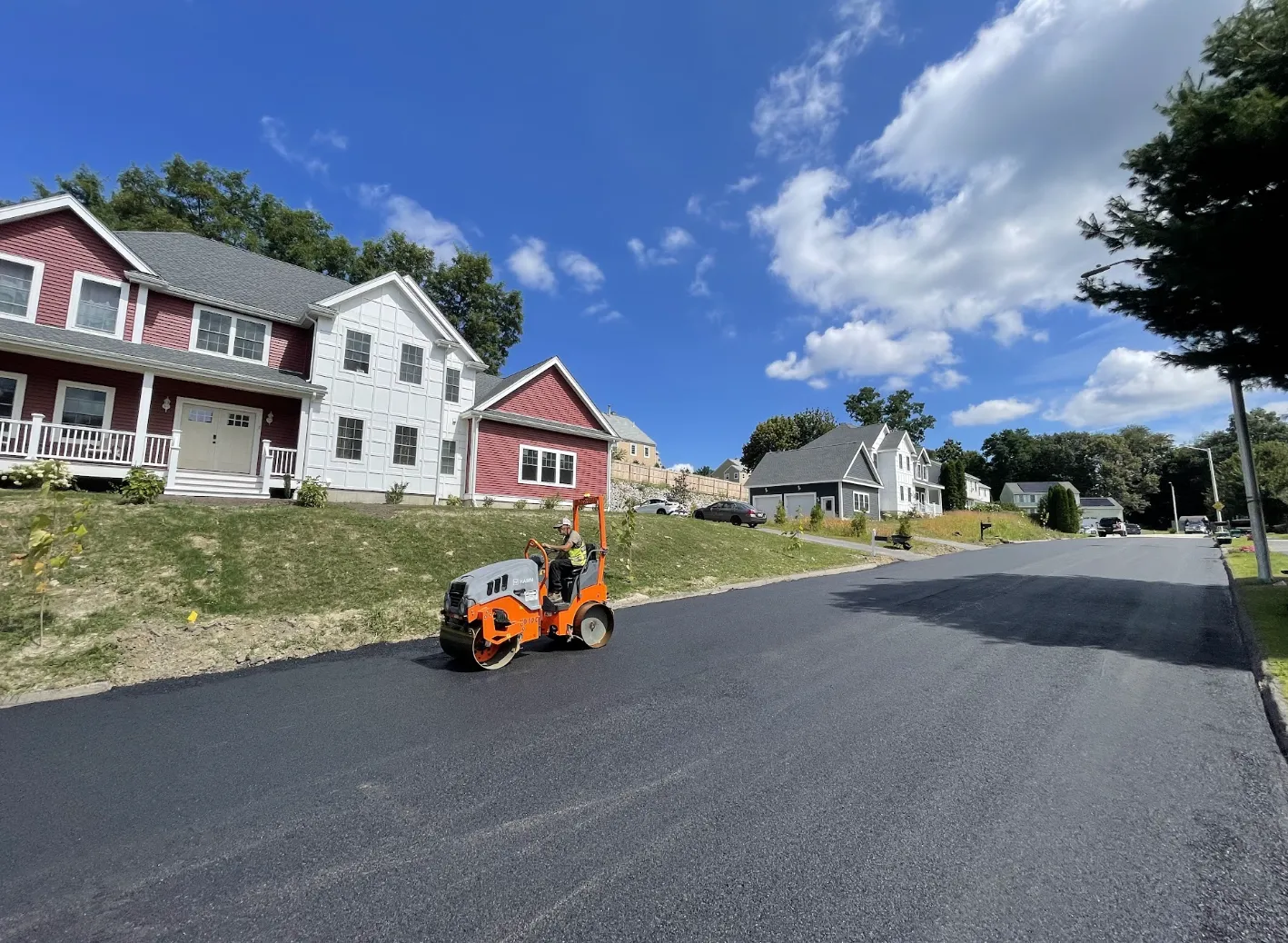 Blacktop Services operator compacting fresh hot-mix asphalt on a residential neighborhood street in Rutland MA.