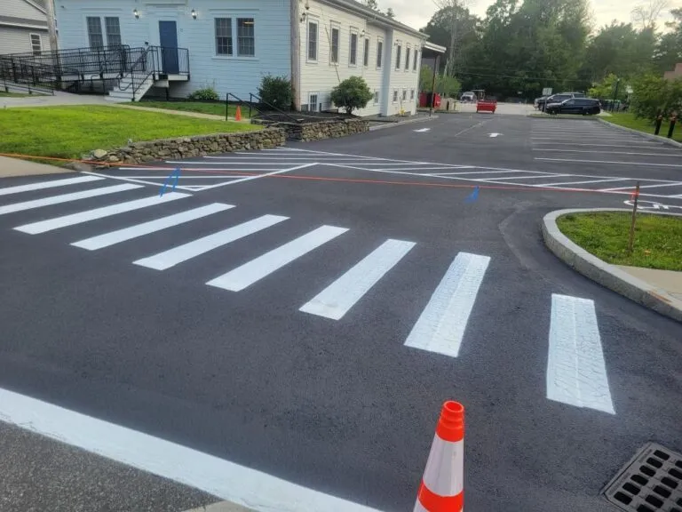 Freshly repaved and line-striped asphalt parking lot with a pedestrian crosswalk in Athol MA by Blacktop Services